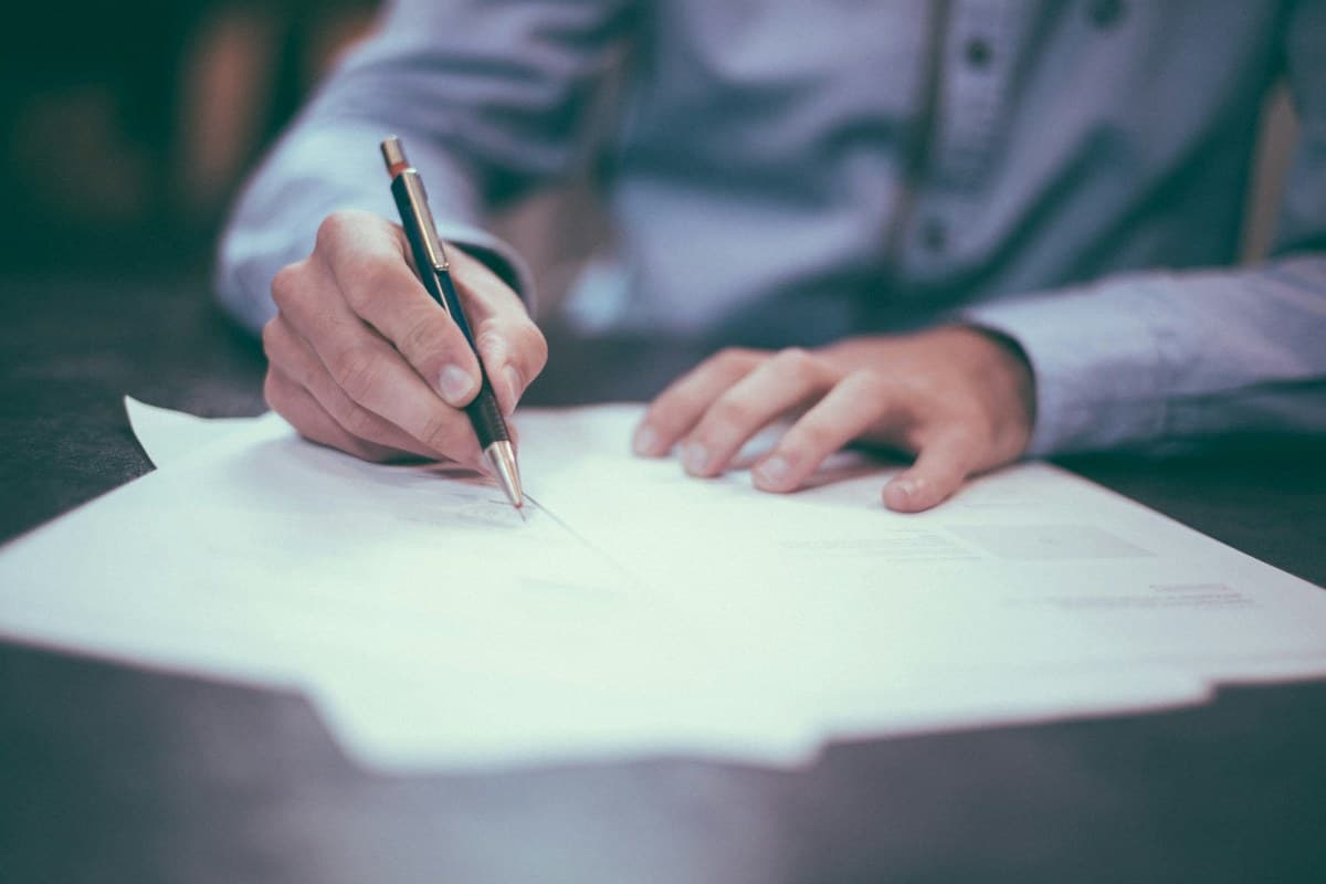 A person writing important documents at a desk